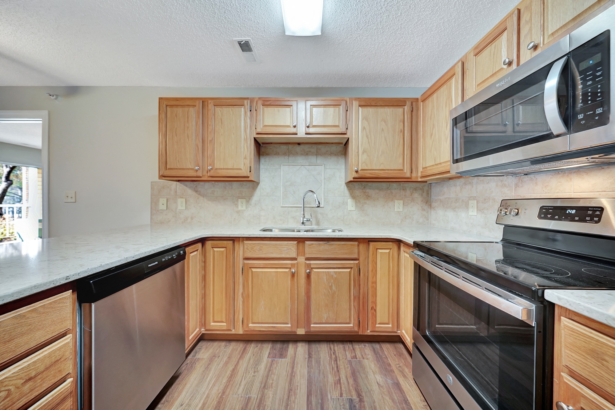 an empty kitchen with wooden cabinets and stainless steel appliances